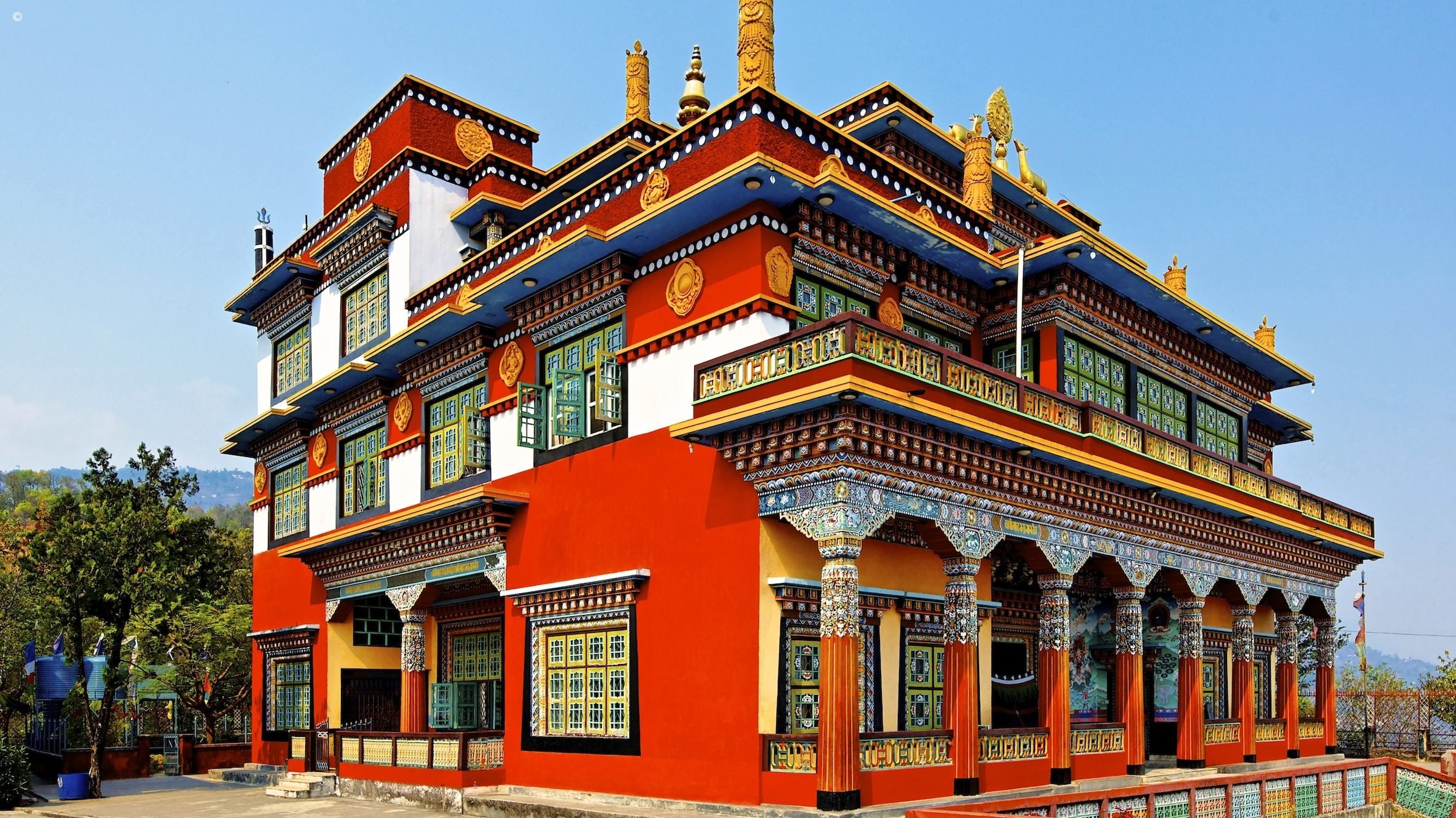  A colorful two-story Buddhist temple with intricate carvings and statues of deities.